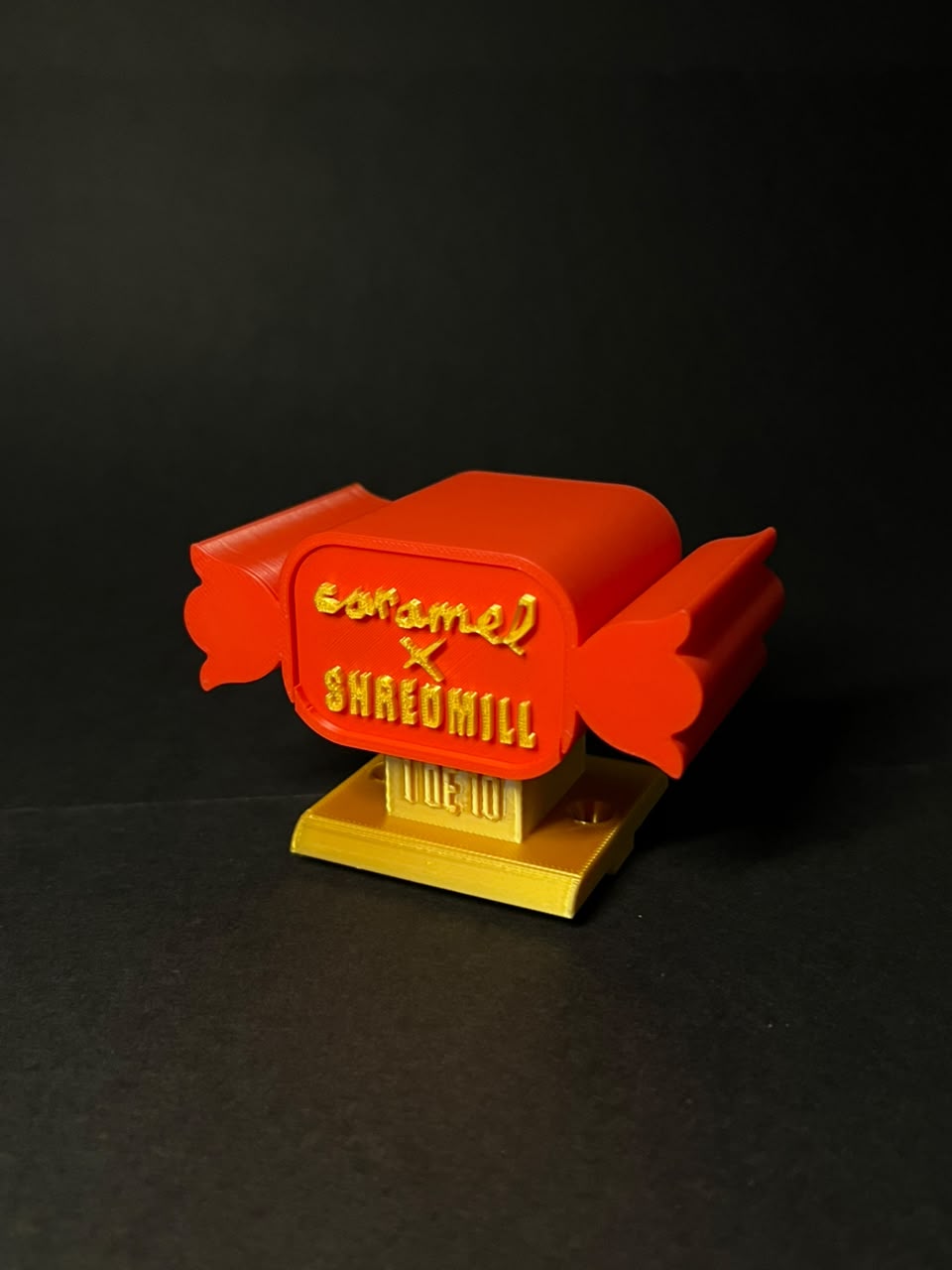 Red and gold Caramel × Shredmill piece with its lid in place